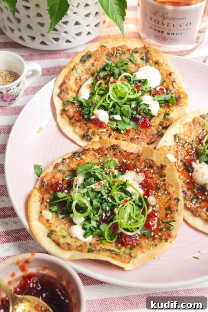 Smash Shrimp Toast Tacos — Crispy Prawn Toast Taco Recipe 8 Three prawn toast tacos topped with herbs and aioli on a pink plate.