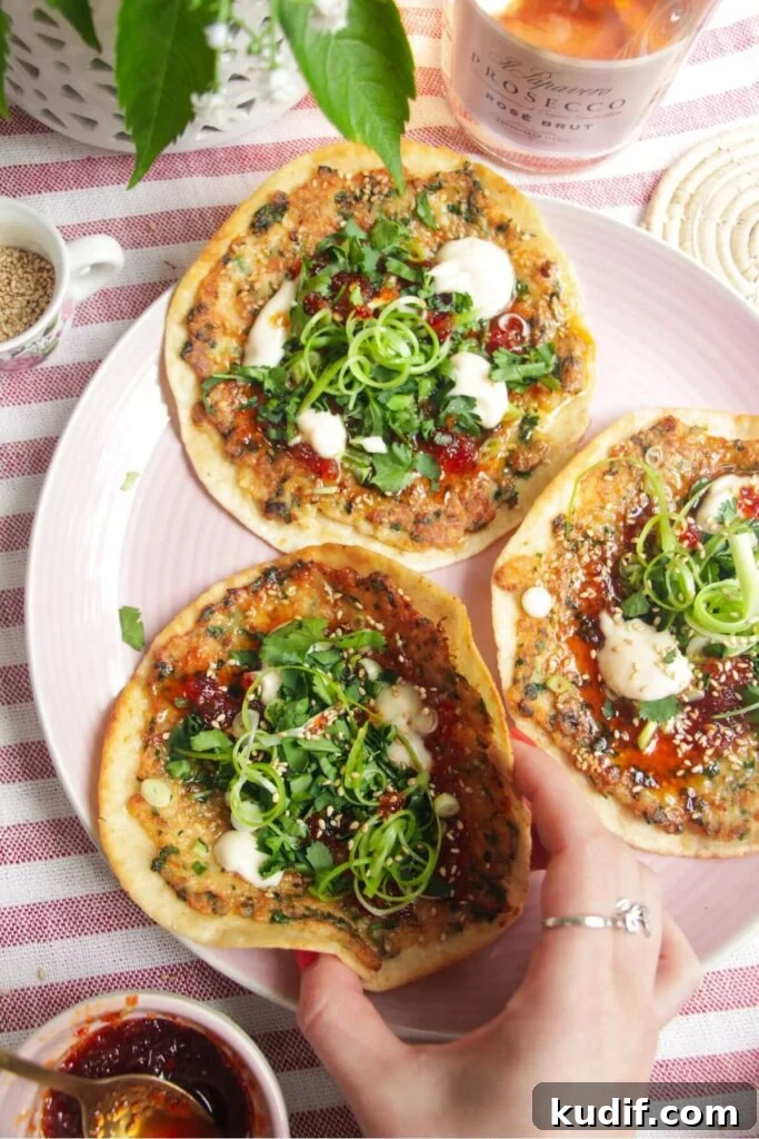 Smash Shrimp Toast Tacos — Crispy Prawn Toast Taco Recipe 9 Three prawn toast tacos topped with herbs and aioli on a pink plate.