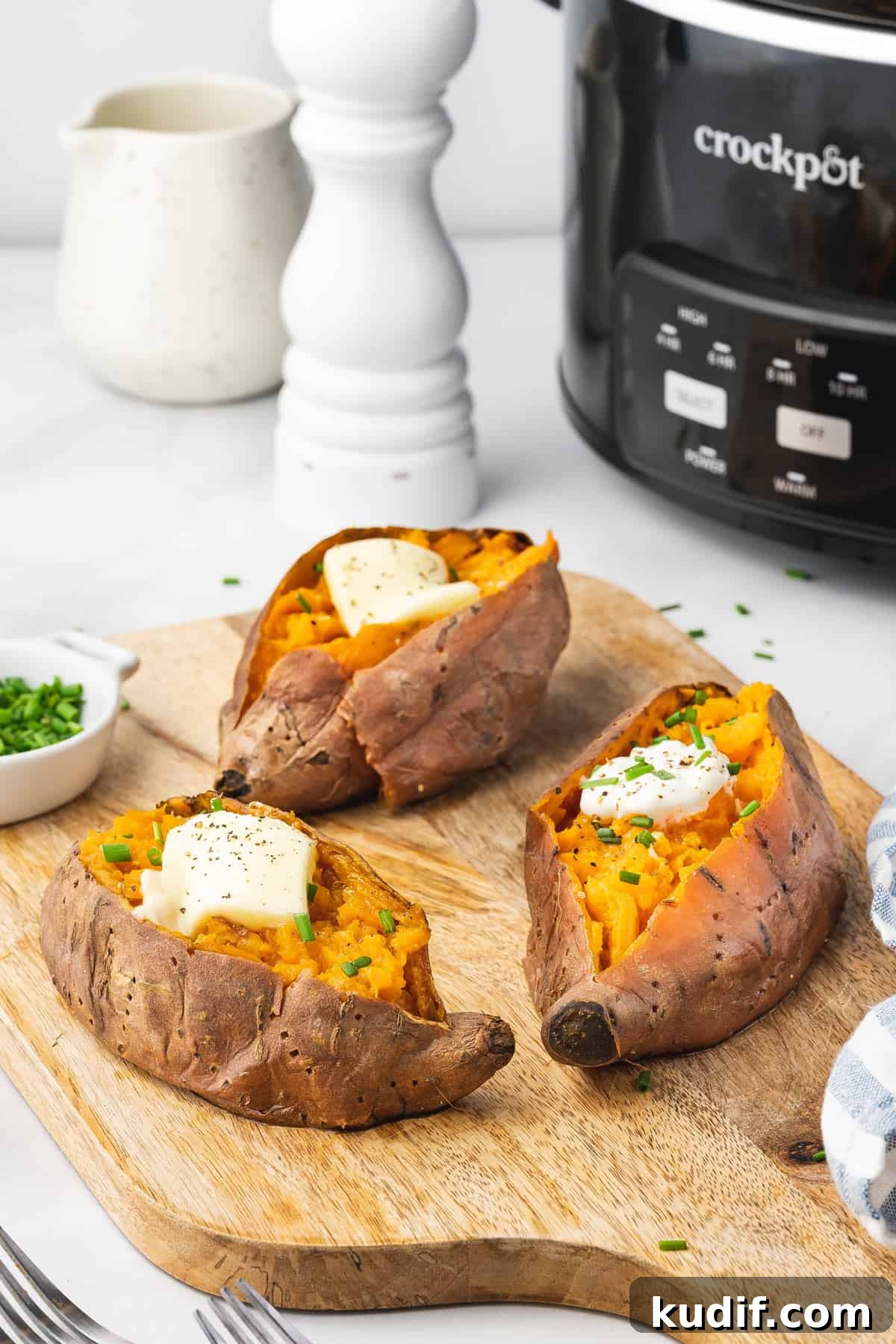 Slow Cooker Mashed Sweet Potatoes Recipe for Weeknight Meals 3 Three slow cooker sweet potatoes with butter and chives on top.