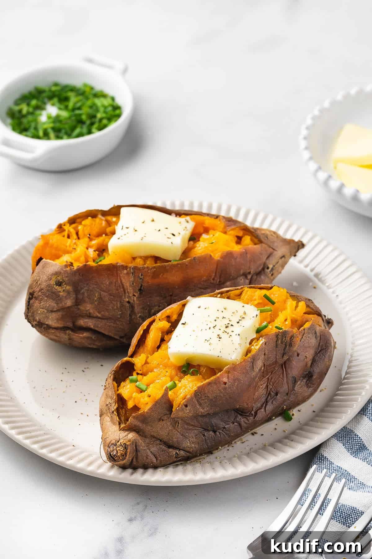 Slow Cooker Mashed Sweet Potatoes Recipe for Weeknight Meals 8 A plate with two slow cooker sweet potatoes with butter and chives on top.