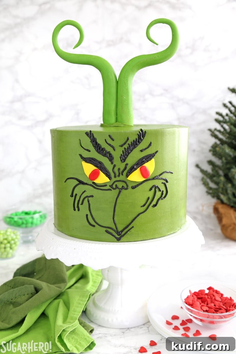 Grinch Cake - green cake decorated with a Grinch's face and fondant Grinch-like hair | From SugarHero.com