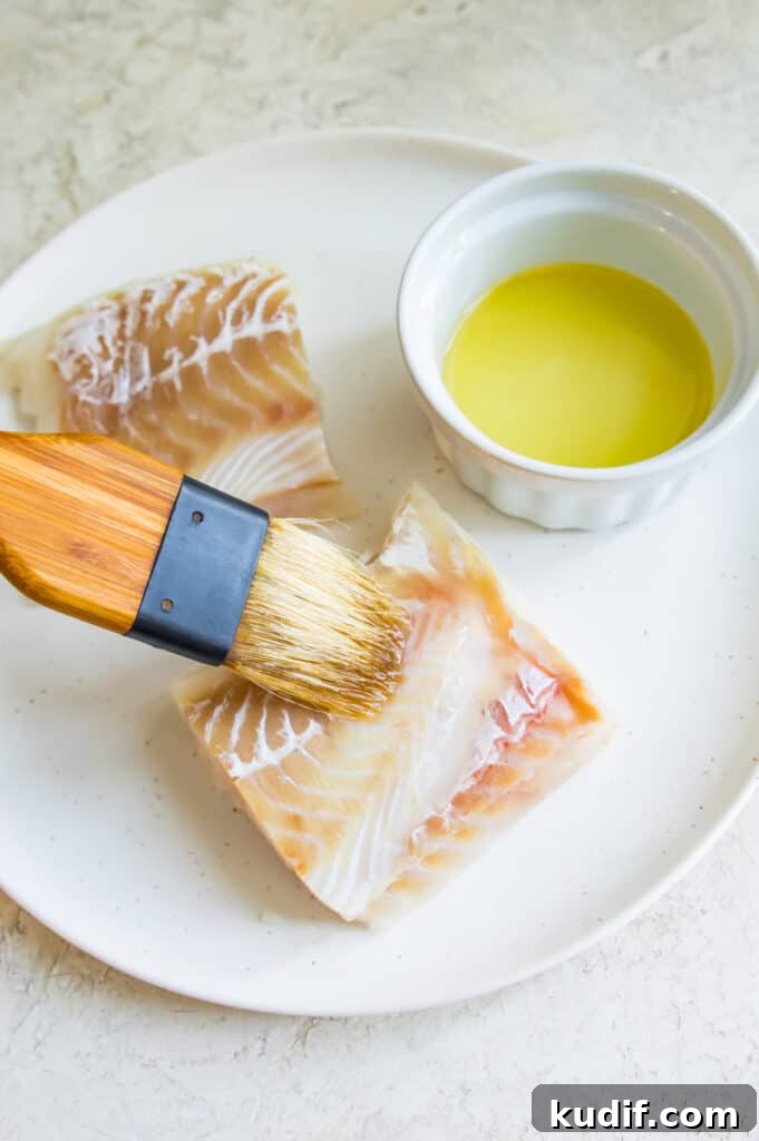 A cod fillet being brushed with oil.