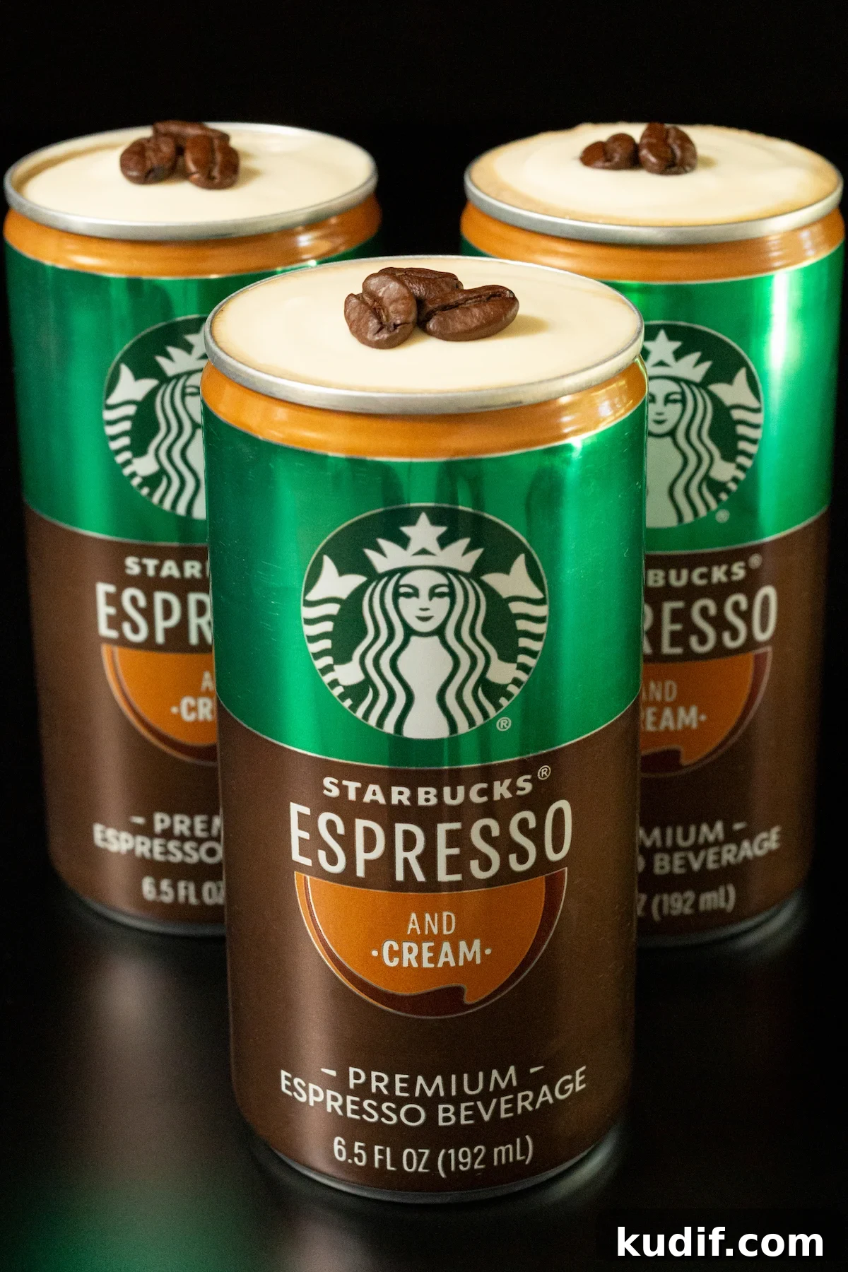 Three Starbucks Espresso and cream cans, each with the top taken off so that you can see a cold foam that's topped with three espresso beans.
