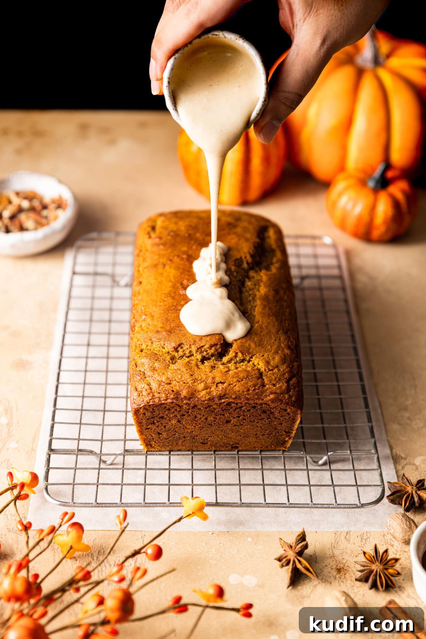 Maple-Glazed Pumpkin Bread Recipe for Fall Baking 9 Maple glaze being poured on top of pumpkin bread loaf