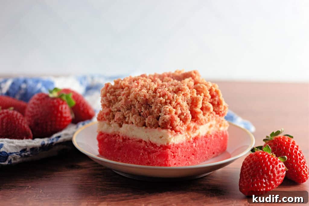 Quick Berry Desserts to Satisfy Sweet Cravings Fast 12 A slice of strawberry crumb cake graces a white plate, embraced by fresh strawberries and a blue-patterned cloth. It captures the essence of delightful strawberry crunch bars on a rustic wooden surface.