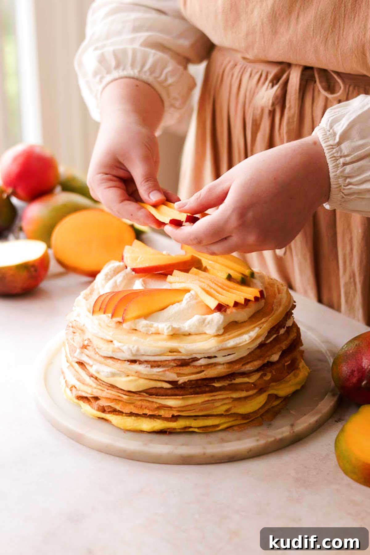 Mango Crepe Cake Recipe with Homemade Crepes Made from Scratch 17 decorating the cake with mango slices