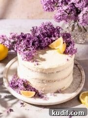 Semi naked layer cake topped with fresh lilacs and lemon wedges