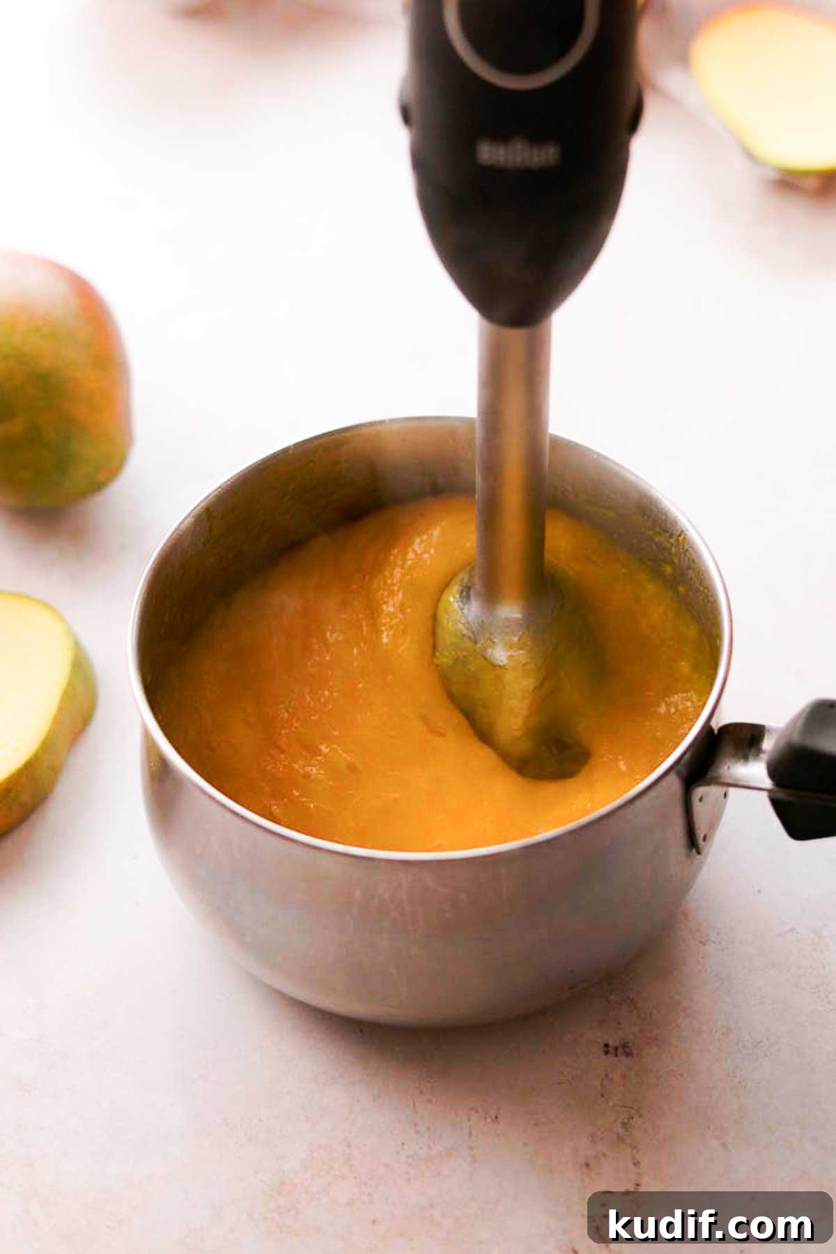 Mango Crepe Cake Recipe with Homemade Crepes Made from Scratch 10 blending mango puree with an immersion hand blender in a saucepan