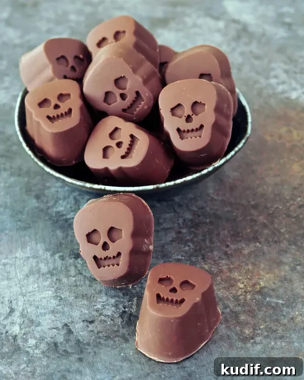 bite size, skull shaped Halloween chocolates stuffed with pumpkin caramel, in a bowl on a dark marbled background