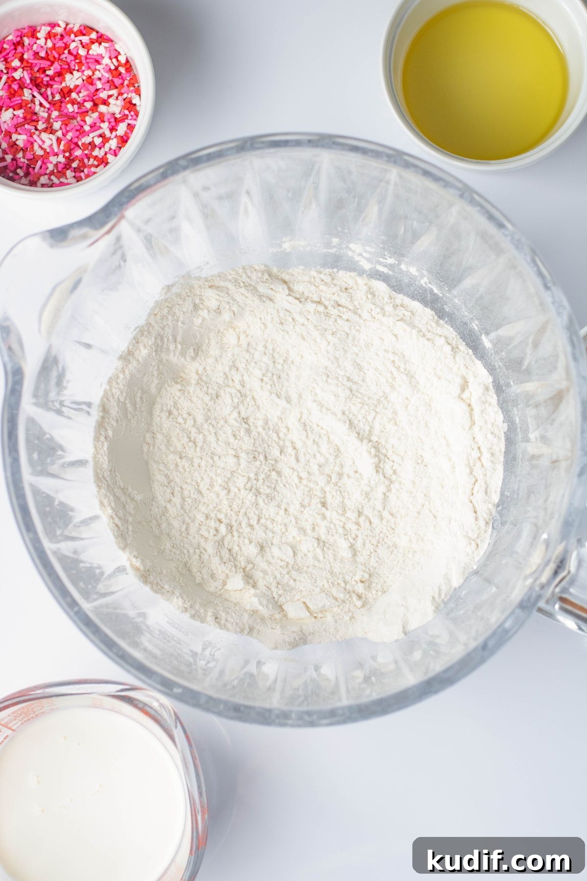 Ingredients in clear bowl, being mixed together before adding in sprinkles. 