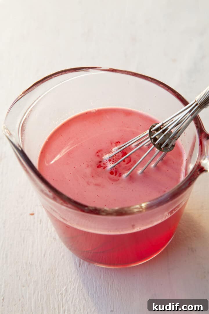 Strawberry Graham Poke Cake Recipe with Creamy Filling 11 strawberry gelatin dissolved into water in a measuring cup.