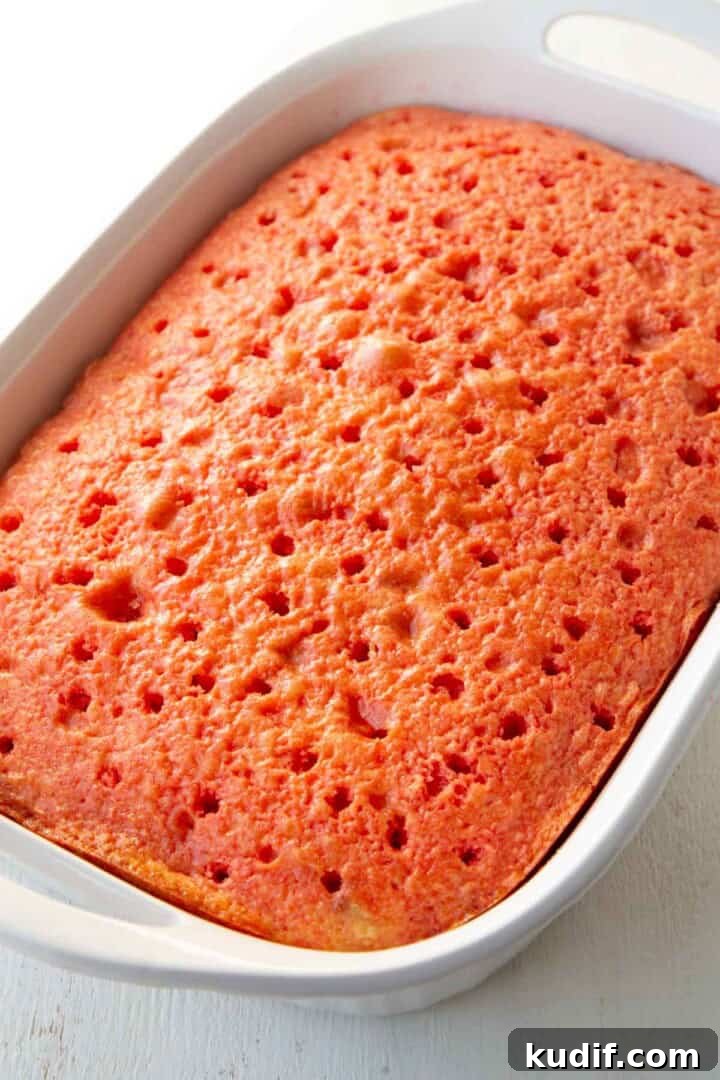 Strawberry Graham Poke Cake Recipe with Creamy Filling 12 yellow cake with holes in it, topped with strawberry gelatin.