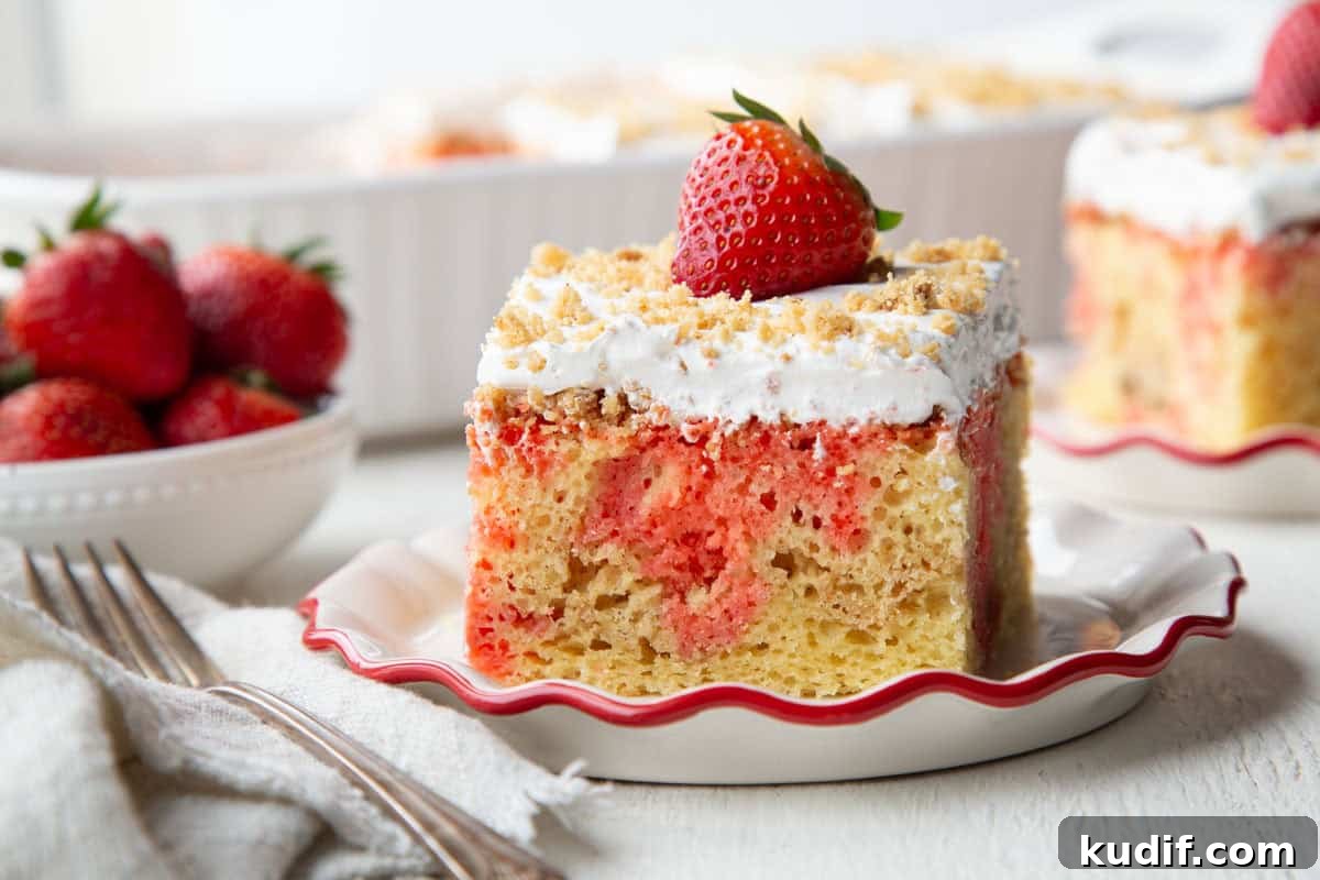 Strawberry Graham Poke Cake Recipe with Creamy Filling 15 slice of poke cake with graham cracker crumbs, whipped topping, and a strawberry on top.
