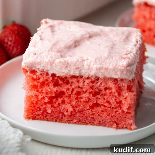 slice of bright pink strawberry cake with a lighter pink strawberry icing.