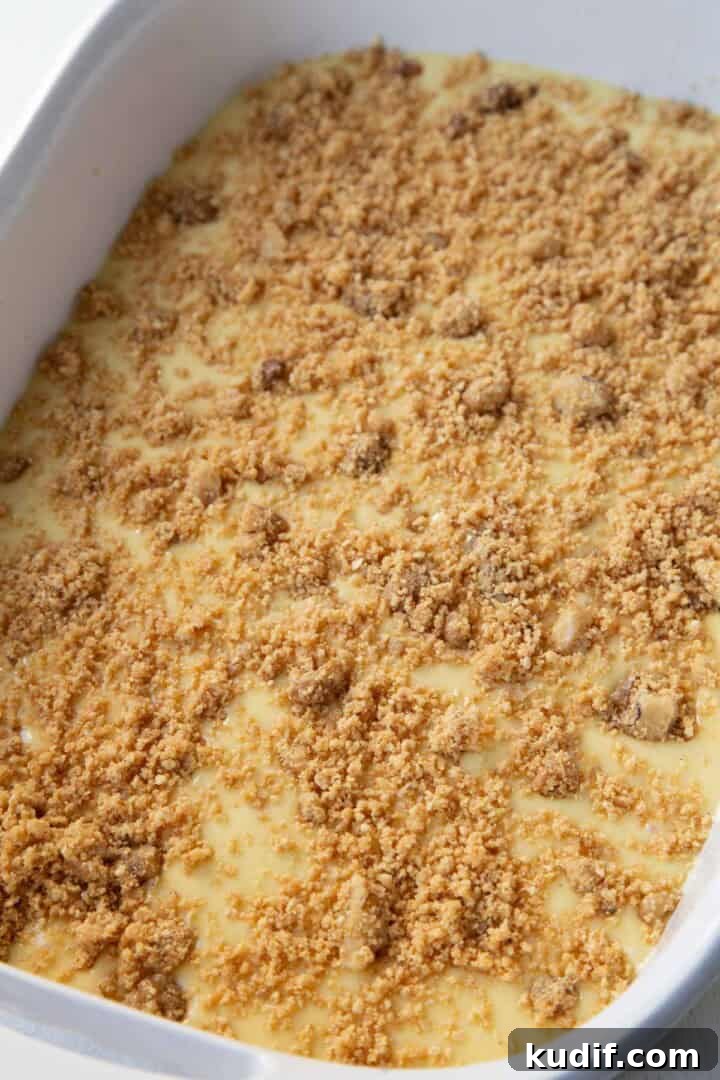 Strawberry Graham Poke Cake Recipe with Creamy Filling 7 cake batter covered with graham cracker crumbs in a baking dish.
