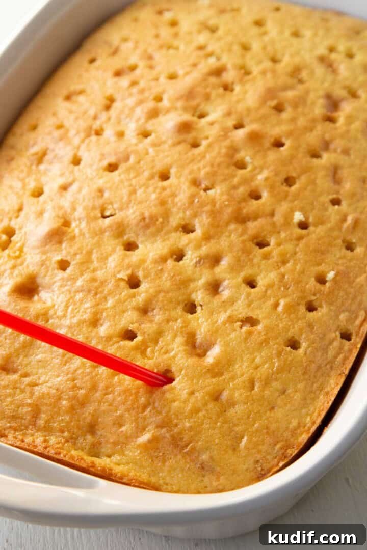 Strawberry Graham Poke Cake Recipe with Creamy Filling 10 straw poking holes in a yellow cake.