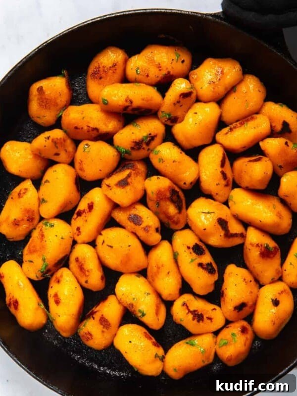 Sweet Potato Gnocchi in black frying pan. Pan is displayed on white background.