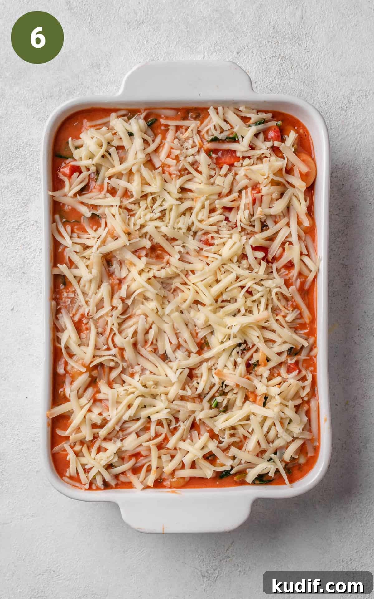 Red sauce with cheese on top in a baking dish.