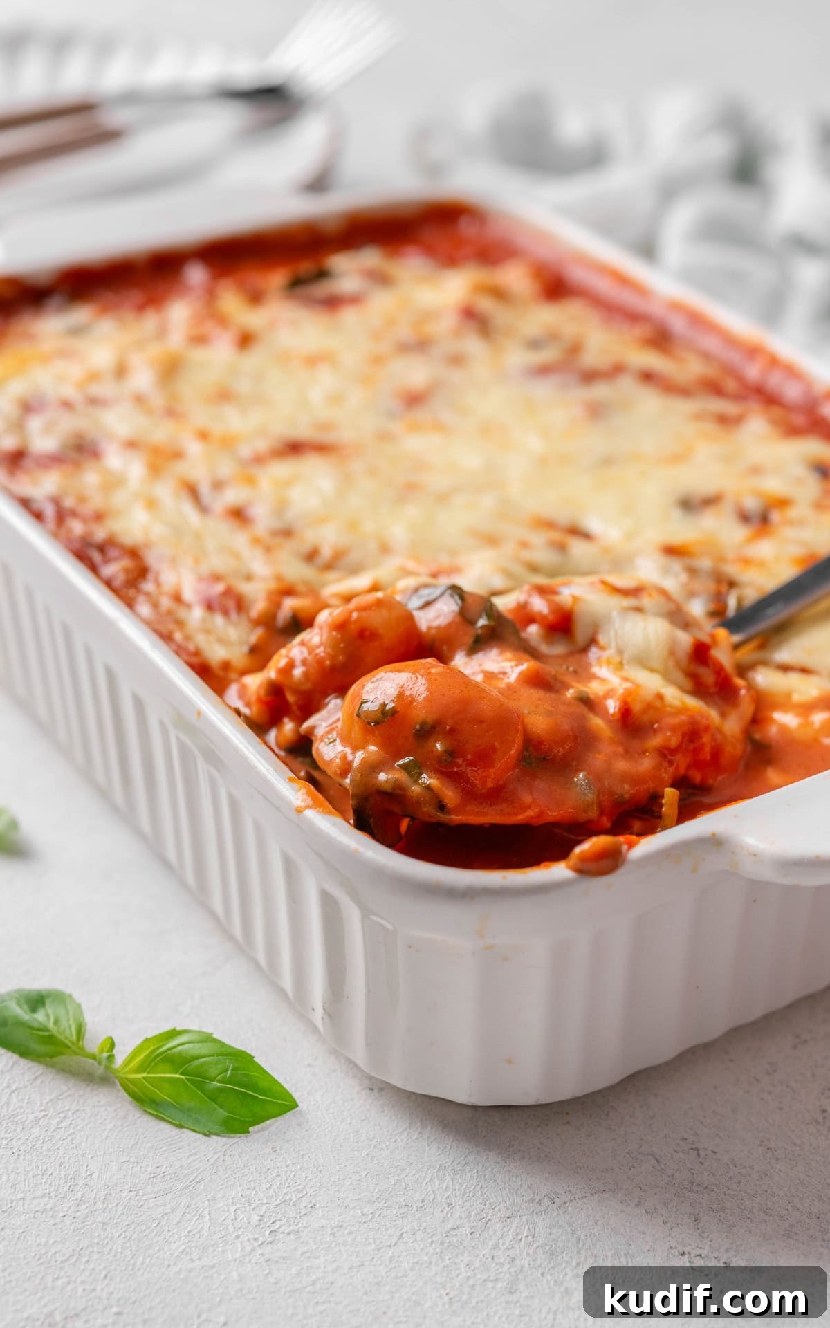 Gnocchi in red sauce with cheese on top in a baking dish.