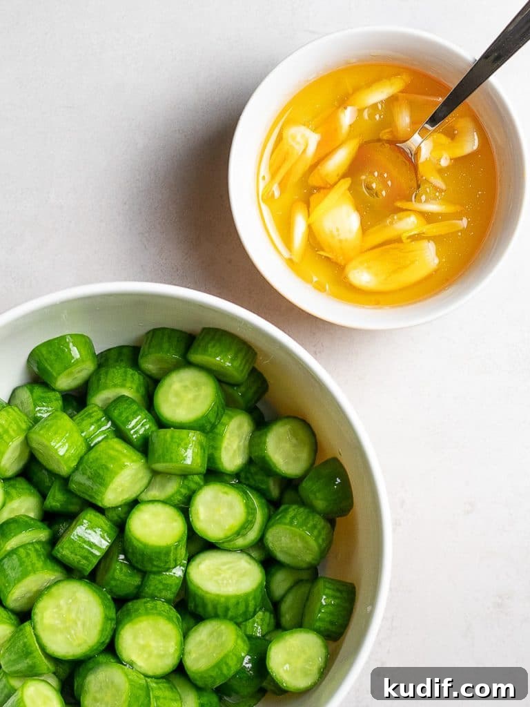 chopped green persian cucumbers in a bowl next to a garlic chili oil dressing