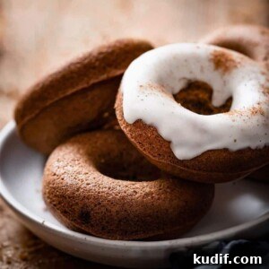 Baked Gingerbread Donuts with Vanilla Glaze 5 Stack of three donuts on a plate, one topped with vanilla icing.