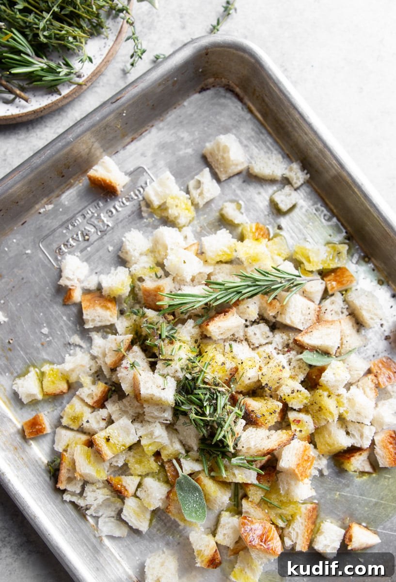 Hearty Turkey, White Bean, and Kale Soup Recipe 4 Bread pieces tossed with olive oil on a baking sheet with fresh rosemary and thyme.