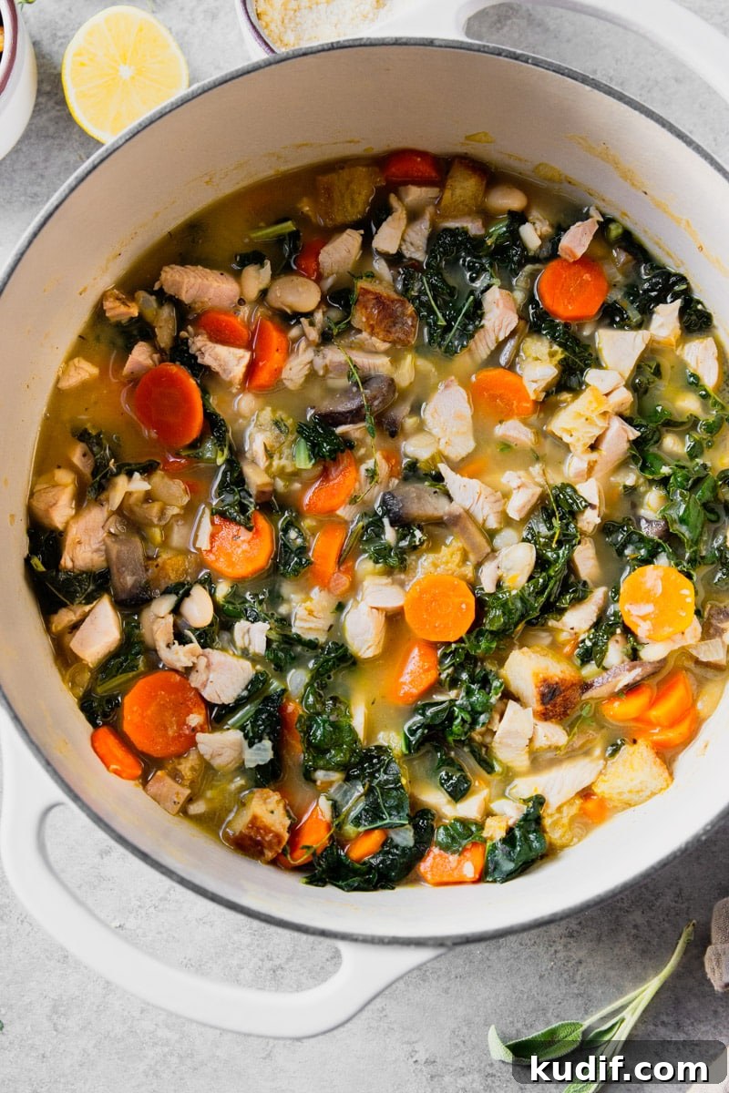 Hearty Turkey, White Bean, and Kale Soup Recipe 8 Turkey white bean soup with kale, mushrooms, carrots in a white pot with a lemon.