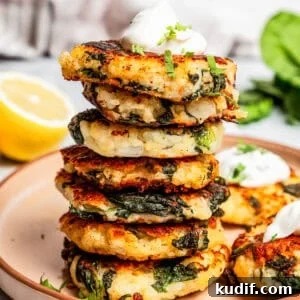 A tall stack of mashed potato pancakes topped with a dollop of sour cream on a plate.