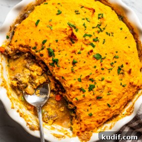 Overhead view of a baking dish with a sweet potato shepherd's pie and a spoon resting inside of the baking dish.
