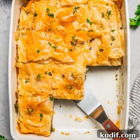 Overhead view of butternut squash and spinach pie in a baking dish, with sliced missing.