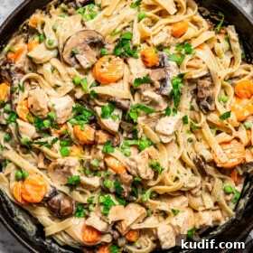 Overhead image of a cast iron skillet filled with pasta and turkey chunks in a creamy sauce to make turkey tetrazzini.