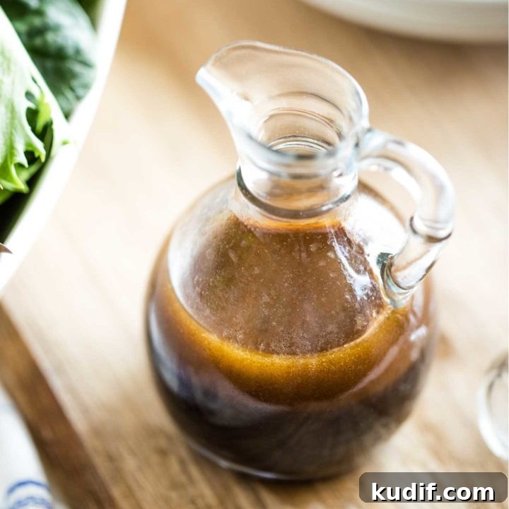 Cruet of salad dressing on a wooden serving board, with a big bowl of salad off to the side nearby