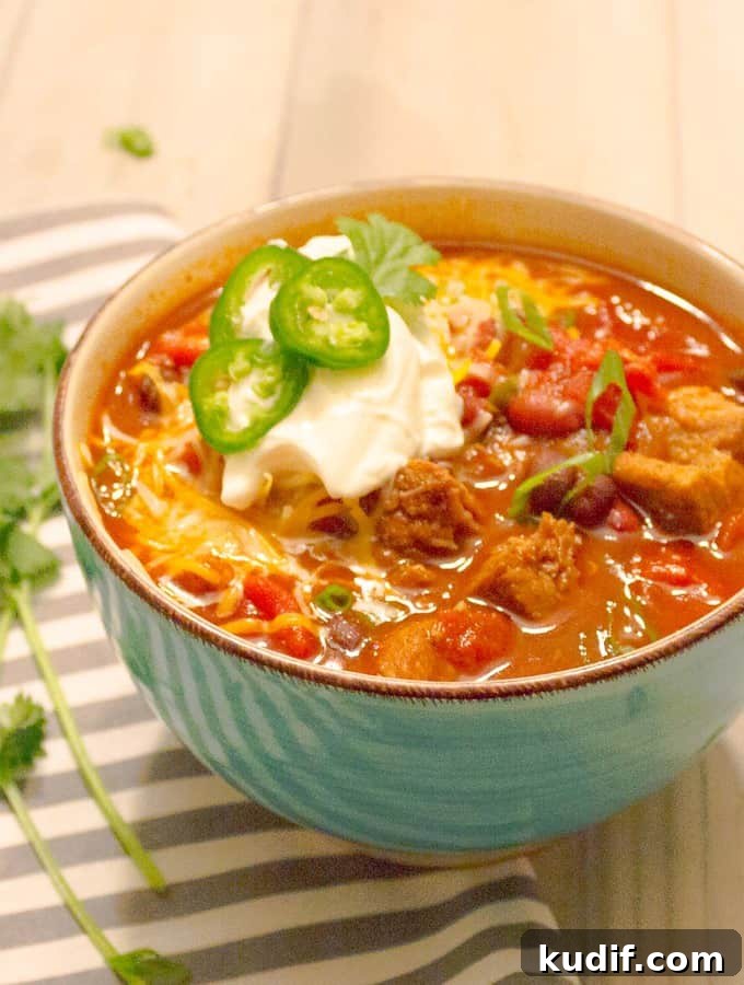 Instant Pot Red Pork Chili Recipe — Quick Pressure Cooker Meal 2 Instant Pot Pressure Cooker Red Pork Chili in a bowl with ganishings in a blue bowl on a gray striped napkin.