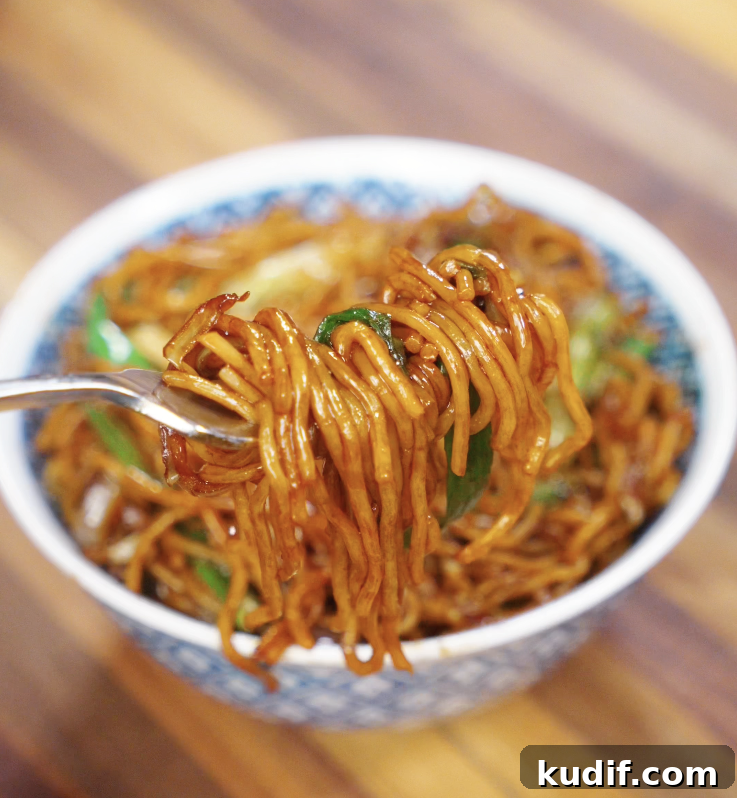 Authentic Chicken Chow Mein Recipe: Quick Stir-Fry Noodles 3 A close-up of chow mein noodles twirled around a fork, highlighting the savory sauce and glistening texture.