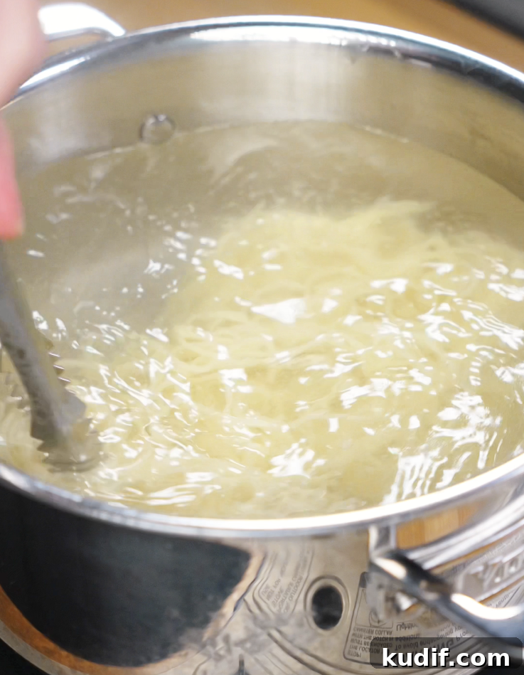 Authentic Chicken Chow Mein Recipe: Quick Stir-Fry Noodles 6 Chow mein noodles swirl in a pot of boiling water, being stirred gently with metal tongs.