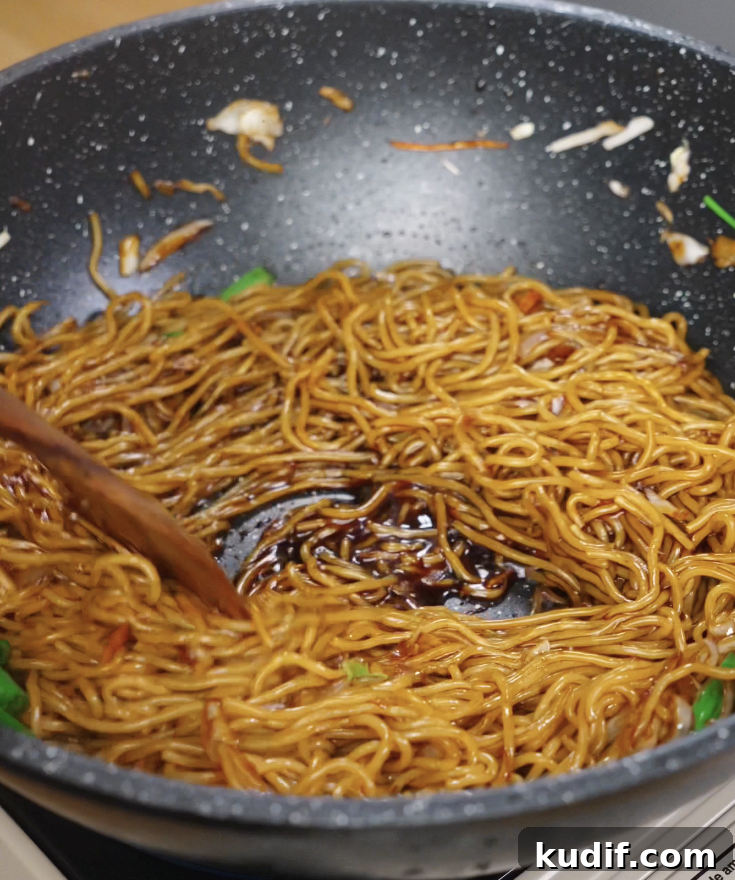 Authentic Chicken Chow Mein Recipe: Quick Stir-Fry Noodles 9 Chow mein noodles are tossed in a wok with sauce and vegetables, forming a ring as the sauce coats the bottom.