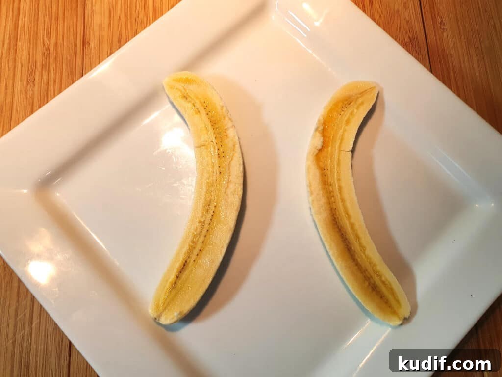 Classic Banana Split Recipe | Step-by-Step Dessert Guide 6 Placing two banana halves on a plate, curves facing outwards, leaving space for the ice cream.