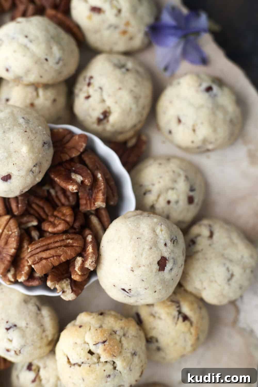 baked pecan Sandies cookies with a small bowl of extra pecans