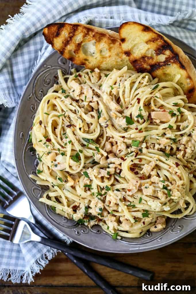 Linguine with clam sauce in a grey bowl with bread