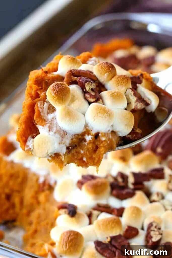sweet potato casserole with marhmallows being spooned out of a casserole