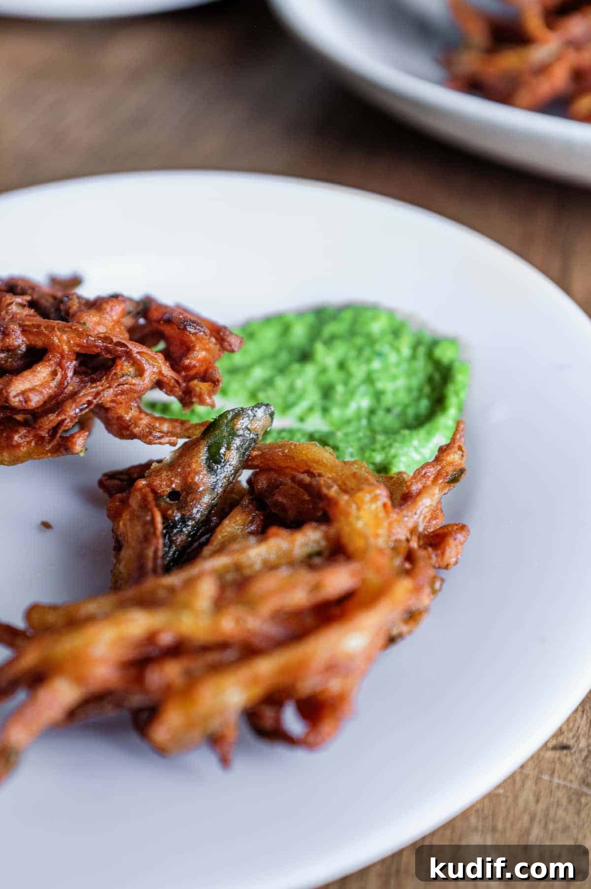 Crispy Onion Pakoda Recipe: Indian Onion Fritters Guide 10 A plate of Indian onion pakoda with a dollop of coriander chutney