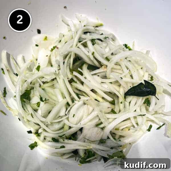 Crispy Onion Pakoda Recipe: Indian Onion Fritters Guide 3 Sliced onions are mixed with fresh coriander and curry leaves in a bowl