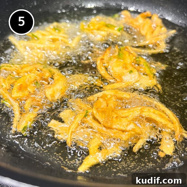 Crispy Onion Pakoda Recipe: Indian Onion Fritters Guide 6 Four onion pakoda frying in oil in a pan