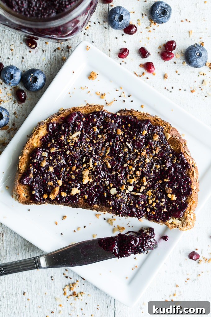 Overhead view of Blueberry Pomegranate Chia Jam on a slice of toast that's on a white plate.