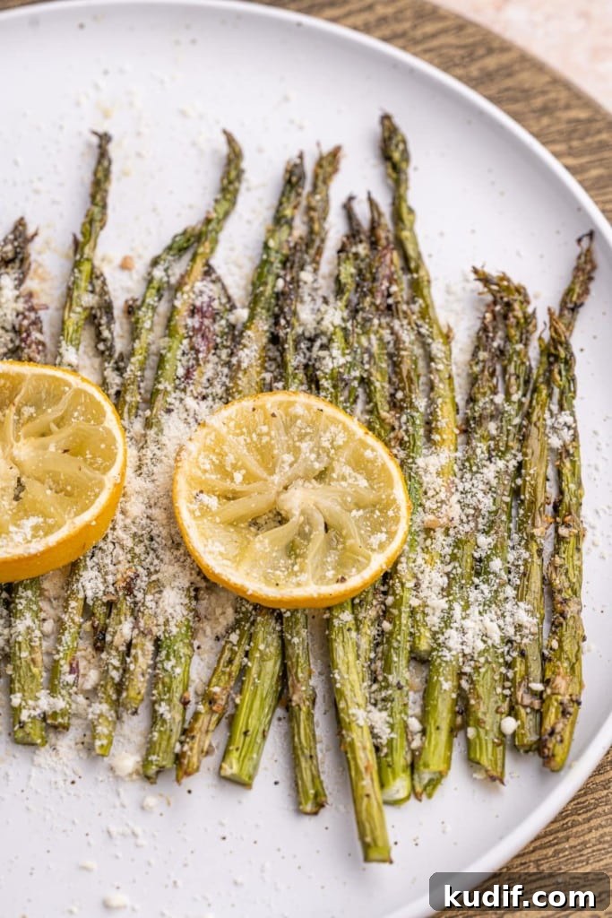 20-Minute Garlic Lemon Asparagus Recipe for Quick Weeknight Sides 2 Close up of Garlic Lemon Asparagus on a white plate with two slices of lemon on top