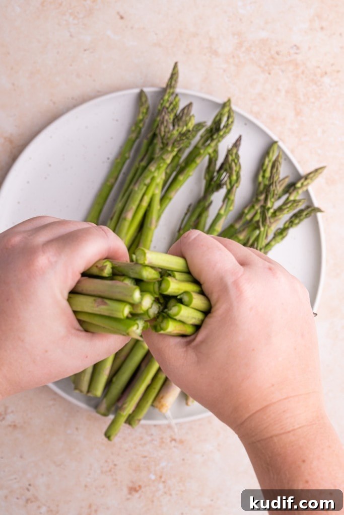 20-Minute Garlic Lemon Asparagus Recipe for Quick Weeknight Sides 5 using two hands to snap asparagus at woody ends
