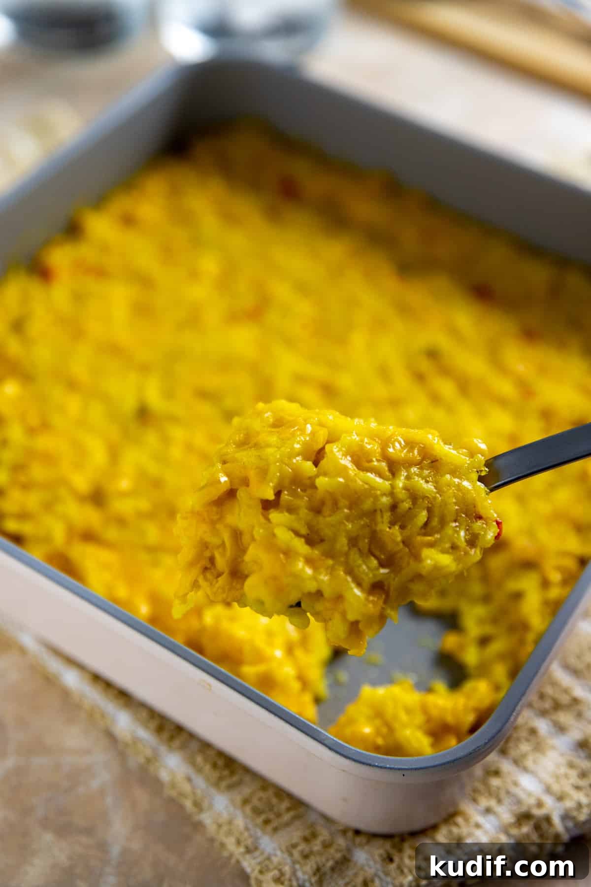 Cheesy Corn and Rice Casserole with Bacon and Green Chiles 2 Square pan with cooked corn and rice casserole. Spoon scooping out a serving.