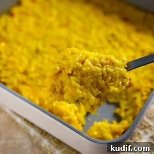 Cheesy Corn and Rice Casserole with Bacon and Green Chiles 9 Square pan with cooked corn and rice casserole. Spoon scooping out a serving.