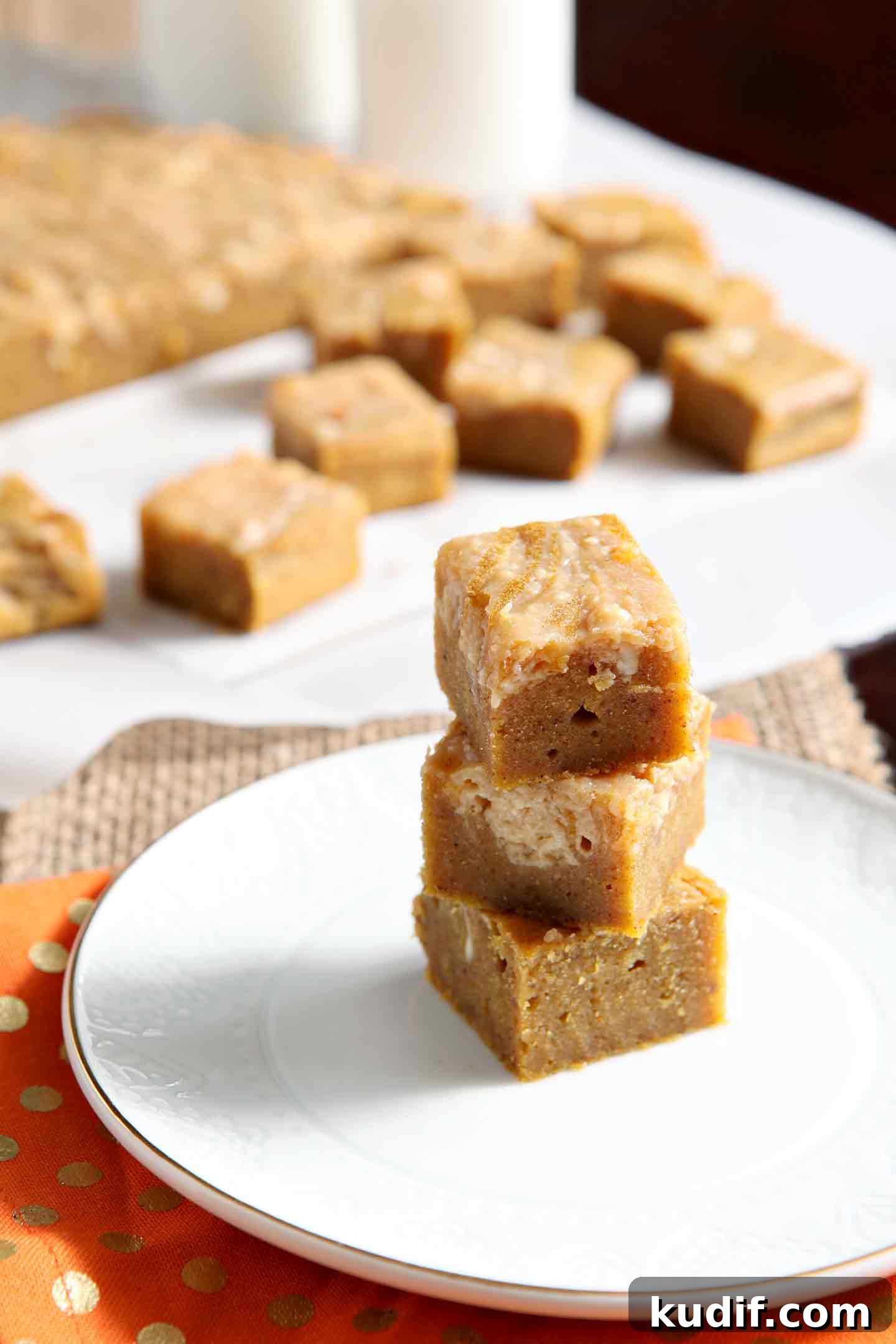 Pumpkin Blondies with Caramel Cream Cheese Swirl Recipe 3 Close up of stacked blondies on a plate, with others in the background