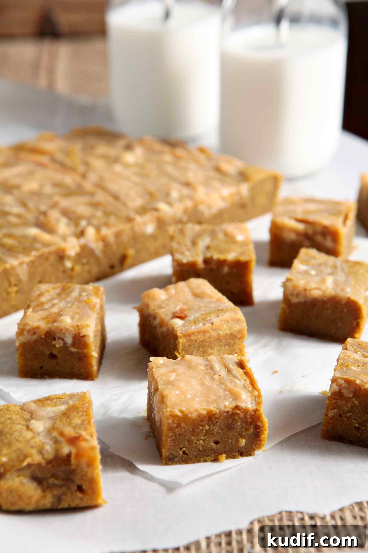 Pumpkin Blondies with Caramel Cream Cheese Swirl Recipe 5 Sliced pumpkin blondies, from the side, with jugs of milk